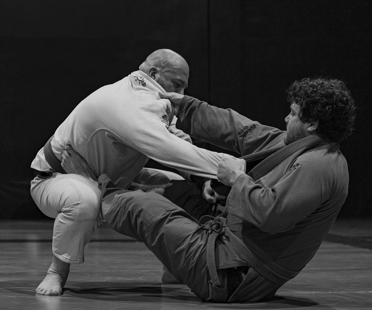 Dois atletas de kimono disputando pegada em uma luta de jiu-jitsu